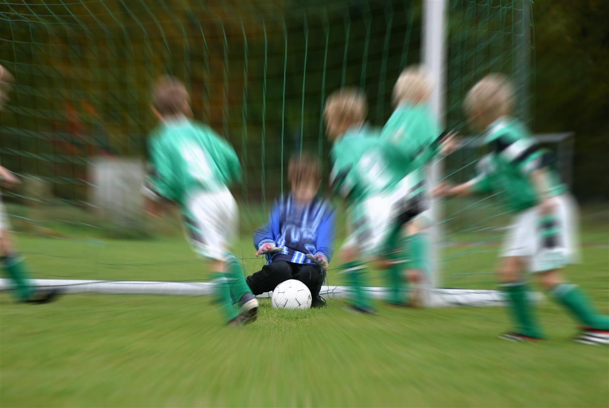 Unger som spiller fotball og en keeper som fanger ballen - Klikk for stort bilde